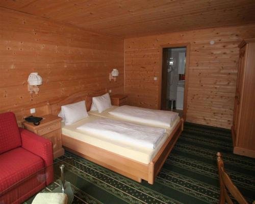 伊布斯河畔格施特灵Hotel Waldesruh的一间卧室配有一张床和一张红色的沙发