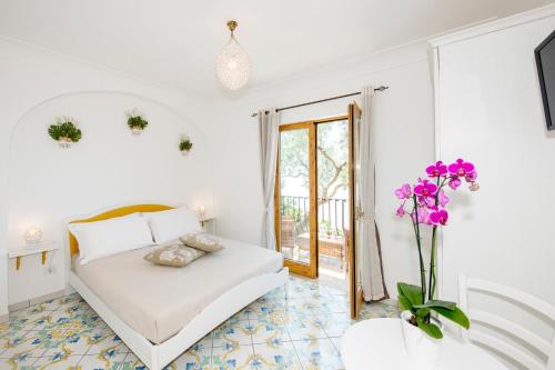 波西塔诺La Borragine Rooms的一间白色的卧室,配有一张床和花瓶