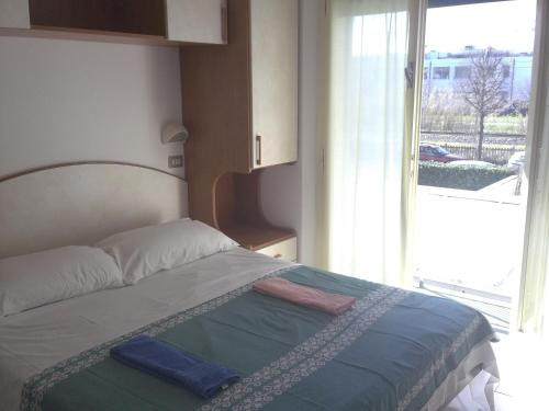 里米尼玛格达酒店的一张位于带大窗户的房间内的床铺