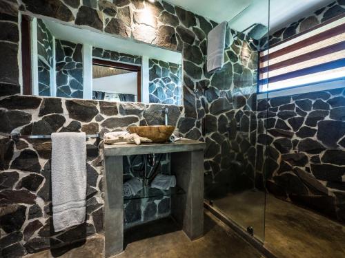 萨玛拉Hotel Peace & Lodge的浴室设有石墙、水槽和镜子