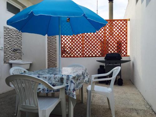 塔维亚诺Appartamento Pompea的一张桌子和两把椅子,配有蓝伞