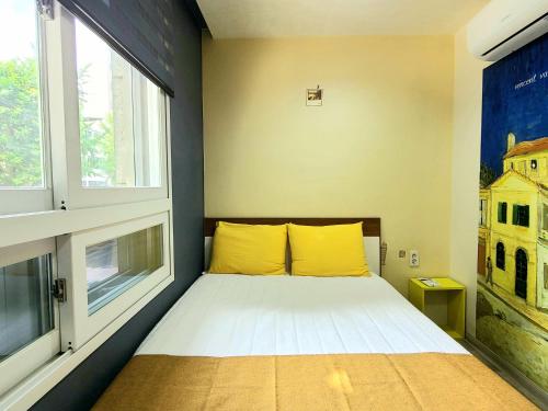 首尔汤米旅舍的一张小床,位于带两个窗户的房间