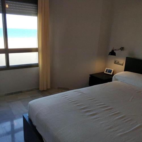 加的斯Victoria Beach Sunset Lounge的卧室配有白色的床和窗户。