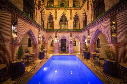 马拉喀什Riad Challa Hotel & Spa的一座带桌椅的室内游泳池