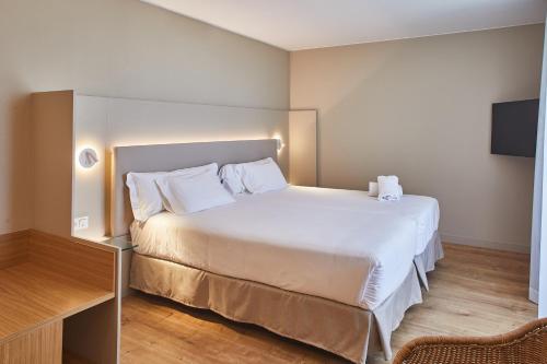 萨拉戈萨阿拉贡斯肯瑞诺酒店的卧室配有白色的床和电视。