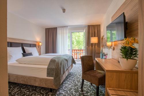 巴德贝芬森Sporthotel Bad Bevensen的酒店客房配有一张床、一张桌子和一把椅子。