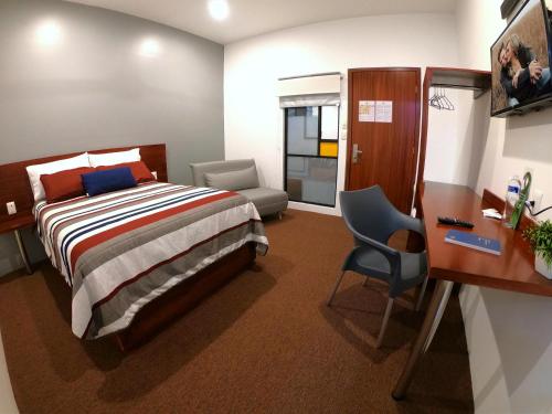 萨卡特卡斯普罗维登酒店的一间卧室配有一张床、一张桌子和一把椅子