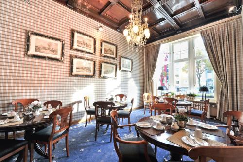 杜塞尔多夫温莎酒店的餐厅设有木桌、椅子和吊灯。