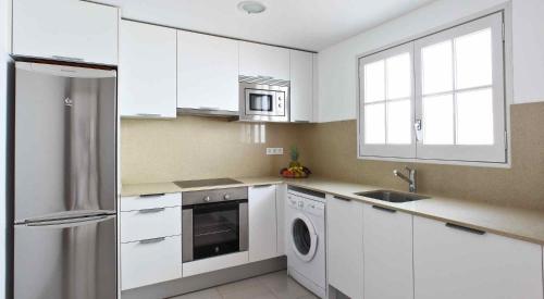 滨海托萨Villa Reymar - diseño y vistas al mar的白色的厨房配有冰箱和洗碗机。