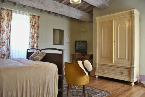 TavoletoPoggio Dei Prugnoli的一间卧室配有一张床、一把椅子和电视