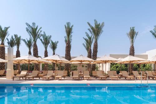 斯代博克Kedma by Isrotel Design的一个带椅子和遮阳伞的游泳池以及棕榈树