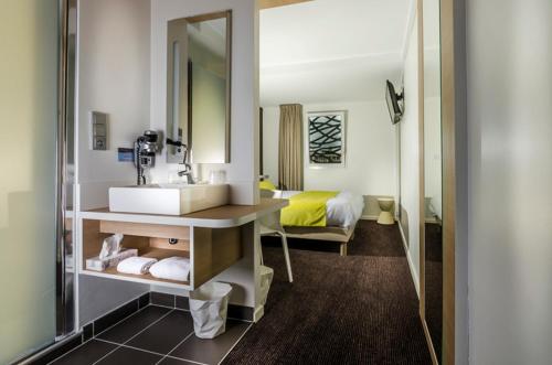 埃尔盖加贝里克Brit Hotel Quimper Nord的一间带水槽和镜子的浴室以及一张床