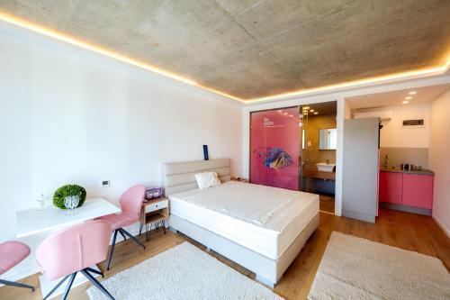 鲍洛托努德沃里A9 Luxury Balatonudvari的一间卧室配有一张床、一张桌子和一张粉红色的椅子