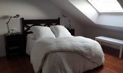 塔皮亚德卡萨列戈Ático en Tapia de Casariego con vistas a la playa.的一间卧室配有一张带白色床单的床和一扇窗户。