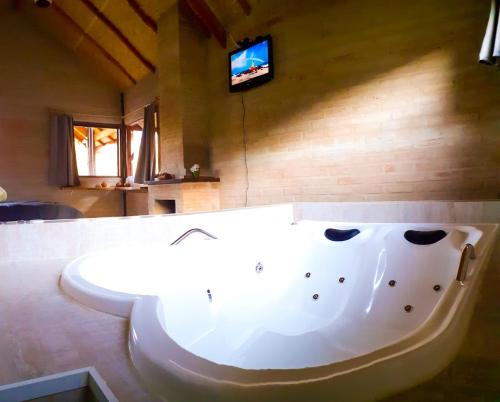 圣安东尼奥-杜皮尼亚尔Chalé na Montanha的带电视的客房内的白色大浴缸