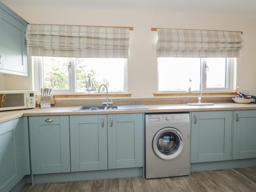 Powfoot2 Whiterow的厨房配有蓝色橱柜和洗衣机。