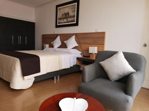 莫约班巴Murano Hotel的一间卧室配有一张床、一把椅子和一张桌子