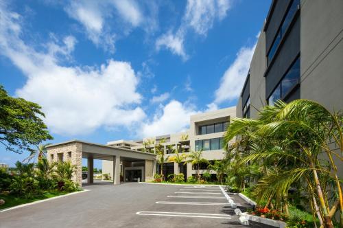 读谷村Glamday Style Okinawa Yomitan Hotel & Resort的一座棕榈树的办公楼