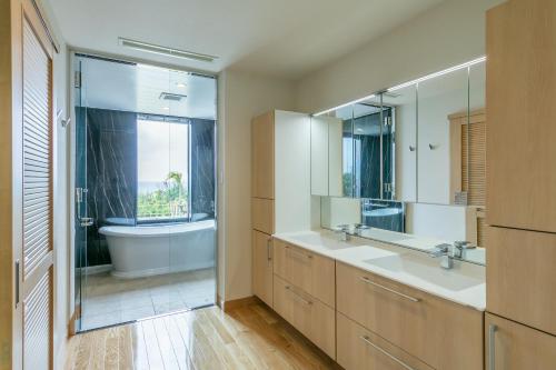 宫古岛Miyakojima Kurima Resort Seawood Hotel的浴室设有2个水槽、浴缸和镜子
