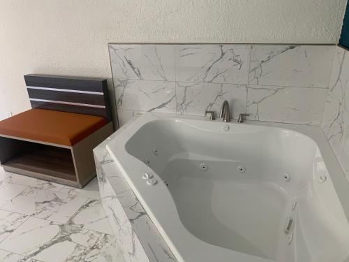 安纳海姆Travel Inn Motel的浴室设有白色浴缸,拥有大理石墙壁。