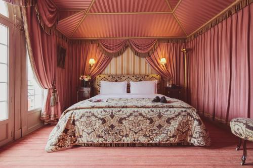 巴黎L酒店的一间卧室配有一张带红色窗帘的大床