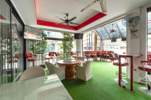 芭堤雅市中心Access Inn Pattaya的一间铺有绿色地毯并配有桌椅的餐厅