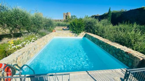 蒙特里久尼蒙特里基欧尼浪漫酒店的一座带石墙的花园内的游泳池