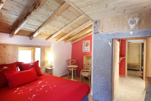 热拉梅Les chalots de Gérardmer, Chambre d'Hôtes的一间卧室配有红色的床和一张桌子