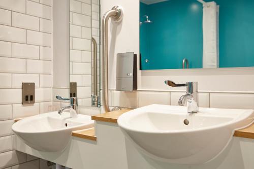 皇家伍顿巴西特The Churchill By Greene King Inns的浴室设有2个白色水槽和蓝色橱柜。