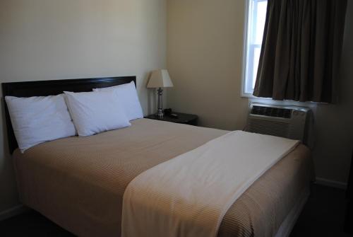 波因特普莱森特海滩岸点汽车旅馆 的一间卧室配有一张带白色床单的床和一扇窗户。