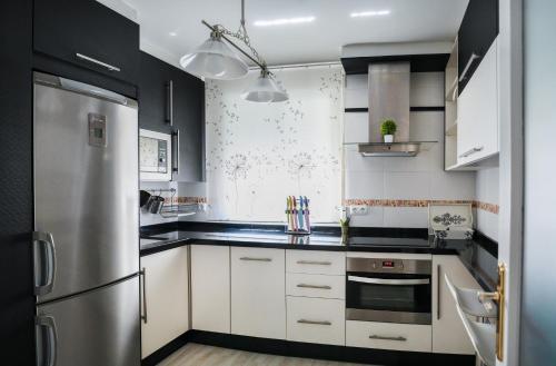 卡索拉Cazorla Suite的厨房配有白色橱柜和不锈钢冰箱