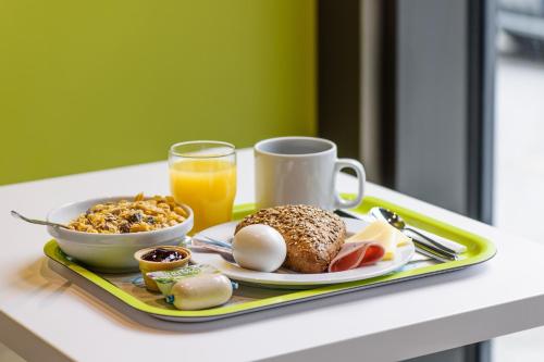 埃尔丁宜必思埃尔丁慕尼黑机场酒店的托盘,包括早餐食品和一杯橙汁