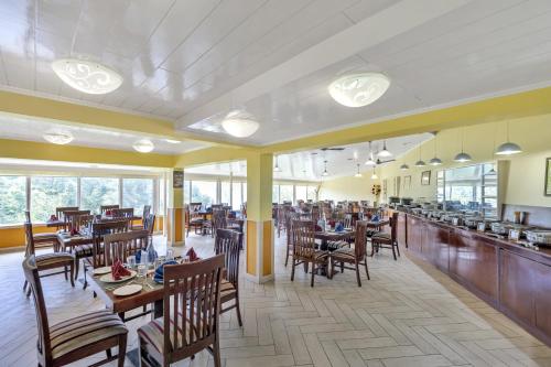 穆索里马辛德拉马苏里度假村的一间带木桌椅的餐厅和一间酒吧