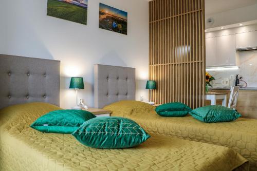 比亚韦斯托克Apartament Podlaskidron的卧室内的两张带绿色枕头的床