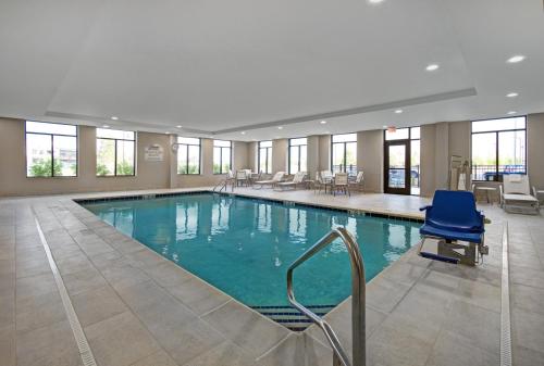 斯特灵海茨Staybridge Suites - Sterling Heights -Detroit Area, an IHG Hotel的一间位于酒店客房内的大型游泳池,配有蓝色椅子