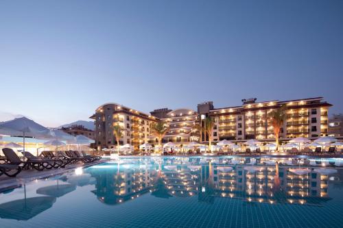 阿拉尼亚Green Garden Resort & Spa Hotel的夜间带椅子和遮阳伞的酒店游泳池