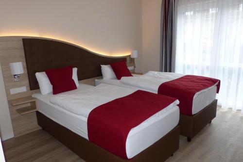 HolmLadiges Gasthof的两张位于酒店客房的床铺,配有红色枕头