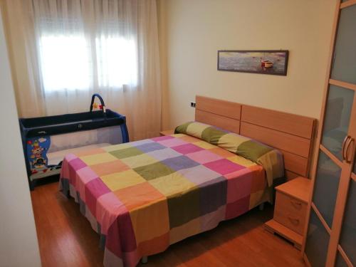 坎布里尔斯Apartamento playa Cambrils edificio Torresol的一间带一张床和一张婴儿床的小卧室