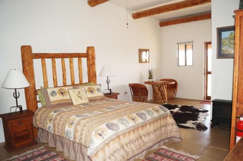 ElginRancho Milagro Bed & Breakfast的卧室配有一张床和一张桌子及椅子