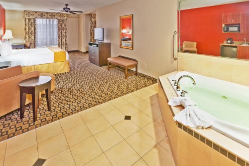 克林顿克林顿智选假日酒店及套房的酒店客房配有一张特大号床和一个浴缸。