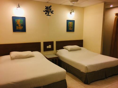 马六甲Coastal Park Hotel的两张床铺,位于酒店客房,墙上有灯