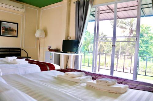 尖竹汶สวนจันท์วาส รีสอร์ท - Suan Chanthwad Resort的酒店客房设有两张床和大窗户。