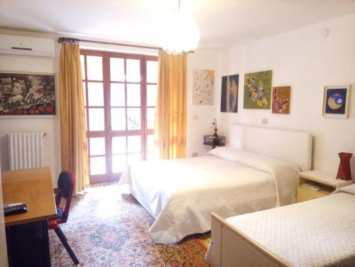 SiliquaVilla Corrias的一间卧室设有两张床、一张桌子和一个窗口。