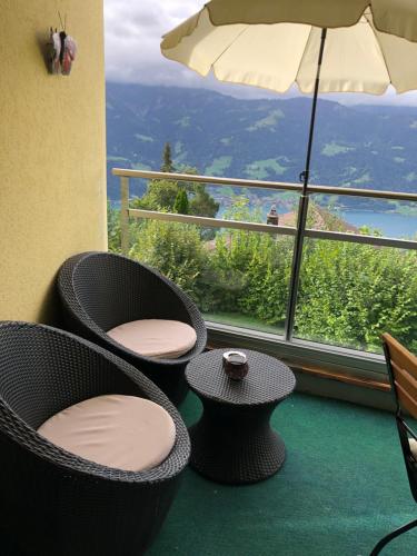贝阿滕贝格Wohnung mit See und Bergsicht im vier Sterne Hotel的美景阳台,配有椅子和遮阳伞