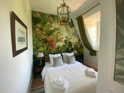 多维尔Magnifique deux pièces au calme的一间卧室配有一张带热带壁纸的大床