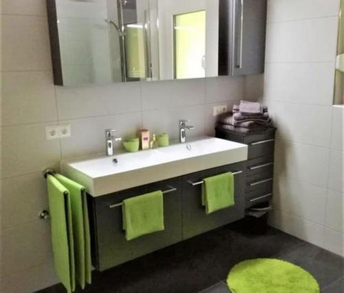克勒希Chalet Auszeit的浴室设有水槽、镜子和绿色毛巾