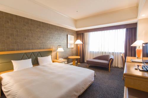 千叶The QUBE Hotel Chiba的酒店客房带一张大床和一把椅子