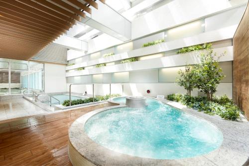 东京Villa Fontaine Grand Tokyo Ariake的一座大型游泳池,位于一座拥有大型天花板的建筑内