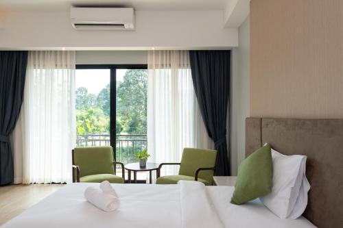 坤西育府Phumontra Resort Nakhon Nayok的一间卧室配有一张带两把椅子的床和一扇窗户