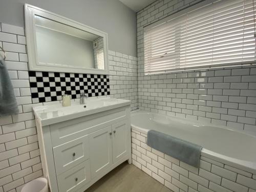 EersterivierstrandNet Hier的一间带水槽、浴缸和镜子的浴室